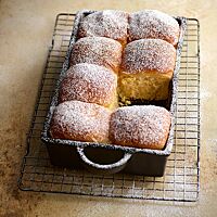 Die mit Puderzucker bestreuten Buchteln wurden angeschoben in einer Auflaufform gebacken und haben eine dünne, glatte Kruste und eine helle, fluffige Krume.