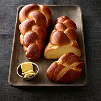Zwei goldbraun glänzende, jeweils aus zwei Strängen geflochtene Milchzöpfe zeigen im Anschnitt die wattig-weiche Krume.