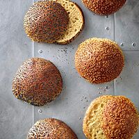 Die mit Sesam bestreuten Hamburgerbrötchen aus hellem Mehl (rechts) und die mit Mohn bestreuten Hamburgerbrötchen mit Vollkornanteil (links) haben eine goldbraun ausgebackene Kruste und eine goldgelbe, lockere Krume.