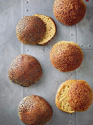 Die mit Sesam bestreuten Hamburgerbrötchen aus hellem Mehl (rechts) und die mit Mohn bestreuten Hamburgerbrötchen mit Vollkornanteil (links) haben eine goldbraun ausgebackene Kruste und eine goldgelbe, lockere Krume.