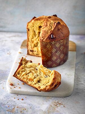 In der hellgelben, faserigen Krume des goldbraun ausgebackenen Panettone sind Sultaninen und Orangeat zu sehen.