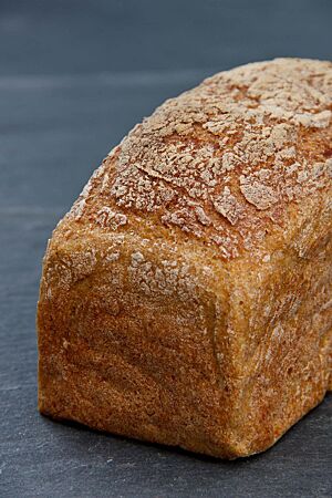 Das glutenfreie Brot wurde in der Kastenform gebacken und hat eine goldbraune, leicht bemehlte Kruste.