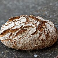 Das kräftig ausgebackene Schwarzwaldbrot mit bemehlter Kruste ist rustikal aufgerissen.