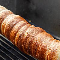 Der vor dem Backen in Zucker gewälzte Sauerteig-Trdelník hat eine goldbraun ausgebackene und glänzende Oberfläche.