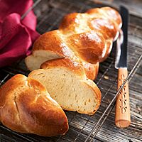 Der Schweizer Zopf liegt im Anschnitt auf einem rechteckigen Gitterrost. Die glänzende, goldbraune Kruste umgibt die helle, elastische, faserige Krume.