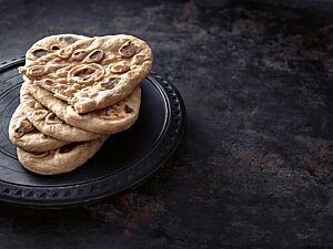 Das ovale Naan hat eine weiche, helle Kruste mit einigen braunen Stellen auf der Oberfläche und eine kleinporige, lockere Krume.
