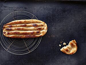 Das längliche, mit Sauerteig gelockerte Tanoori-Fladenbrot hat eine goldgelb ausgebackene Kruste mit goldbraunen Stellen und tiefen länglichen Furchen sowie eine lockere, elastische Krume.