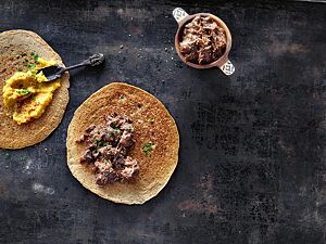 Das Injeera-Fladenbrot mit Linsen-Wot (links) und das Injeera mit Rindfleisch-Wot (rechts) sind sehr dünn, wurden goldbraun ausgebacken und haben eine schwammige, pfannkuchenartige Oberfläche.