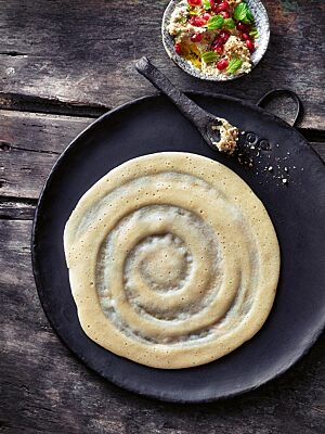 Auf einer Gusseisenplatte liegt ein hellgelb ausgebackener, pfannkuchenähnlicher Laxox-Fladen, auf dessen Oberfläche spiralförmig dicke und dünne Bereiche zu sehen sind. Typischerweise wurde er nur von einer Seite gebacken.