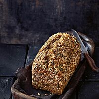 Auf der Kruste des Körnerkasten sind Sonnenblumenkerne, Kürbiskerne, Haferflocken und Leinsaat zu sehen.