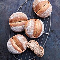 Die Potaten liegen auf einem ovalen Gitter auf einem dunklen Untergrund. Die Krume der leicht bemehlten Brötchen mit einer tiefen Kerbe in der Mitte ist luftig, locker und kleinporig.