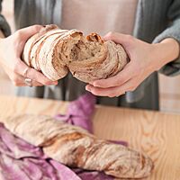 Ein auseinandergebrochenes, in sich verdrehtes Wurzelbrot zeigt die lockere Krume unter der knusprigen Kruste.