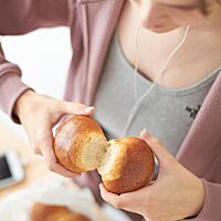 Ein goldbraun ausgebackenes Doppelbrötchen mit glänzender, glatter Oberfläche wird an der Anbackstelle auseinandergebrochen.