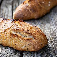 Die Oberfläche der goldbraun ausgebackenen Kartoffelseelen ist mit grobem Salz und Kümmel bestreut.