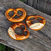 Der Brezelbauch der glänzenden Haferbrezeln ist eingeschnitten (rechts und unten links) oder glatt (oben links).