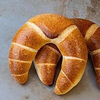 Die glänzende Kruste des Frühstückshörnchens ist goldbraun ausgebacken.